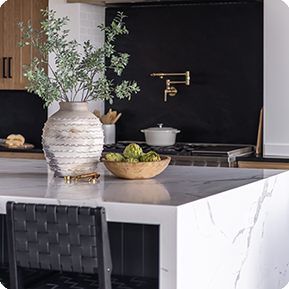 Stylish kitchen island with a polished marble countertop featuring subtle veining, complemented by a decorative vase and fresh produce, illustrating the elegance and practicality of the countertop material.